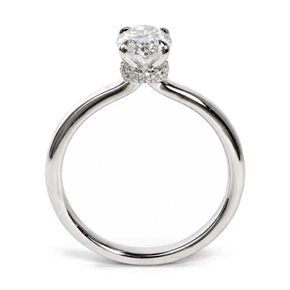 Close-up front angle of a white ring featuring a large oval white gemstone in a 4-prong setting, surrounded by smaller round white gemstones in prong settings along the band.