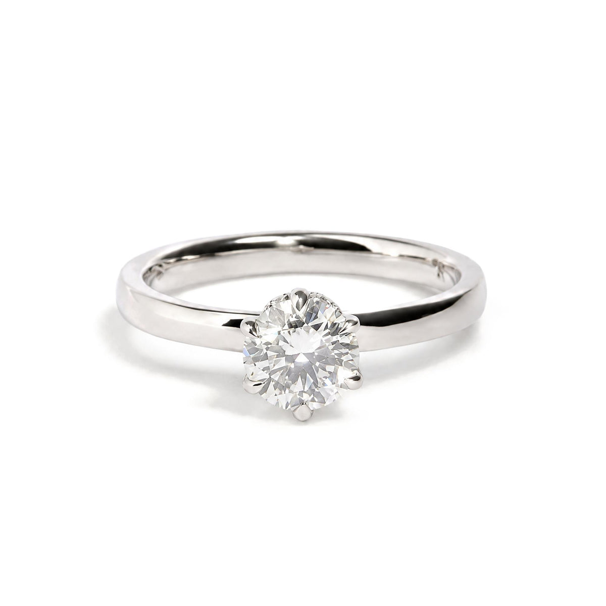 Close-up front angle of a white metal ring featuring a single large round white gemstone in a six-prong setting, surrounded by smaller round white gemstones, shown on a white background.