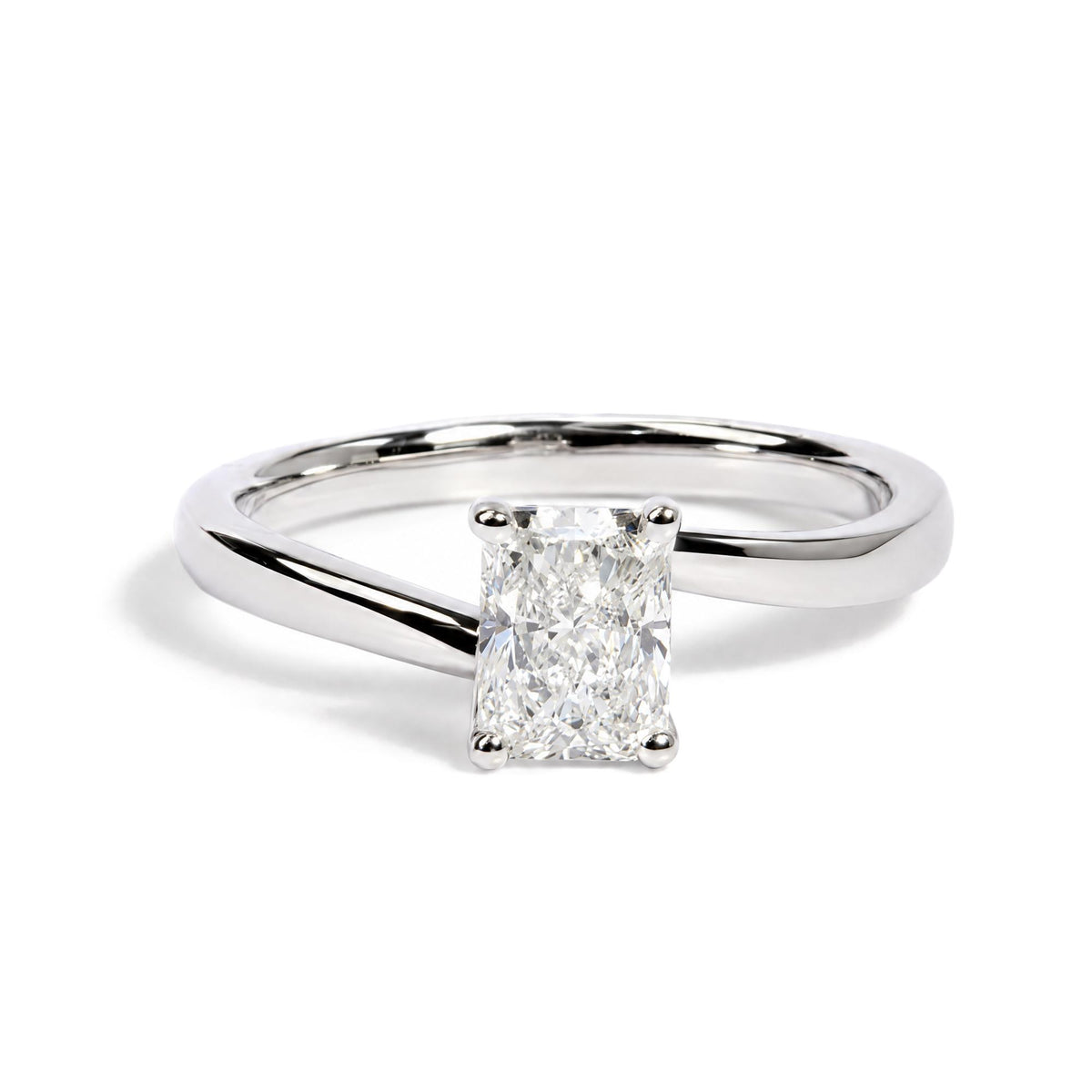Close-up front angle of a white metal ring with a single radiant-shaped white gemstone in a prong setting.