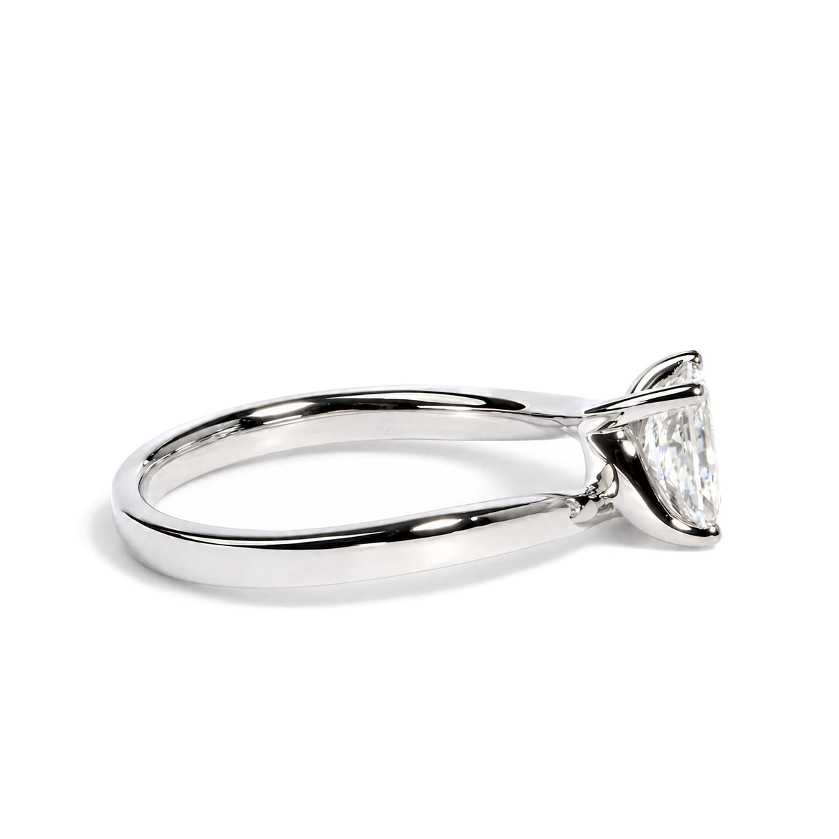 Close-up side angle of a white ring with a radiant-shaped white gemstone set with prongs.