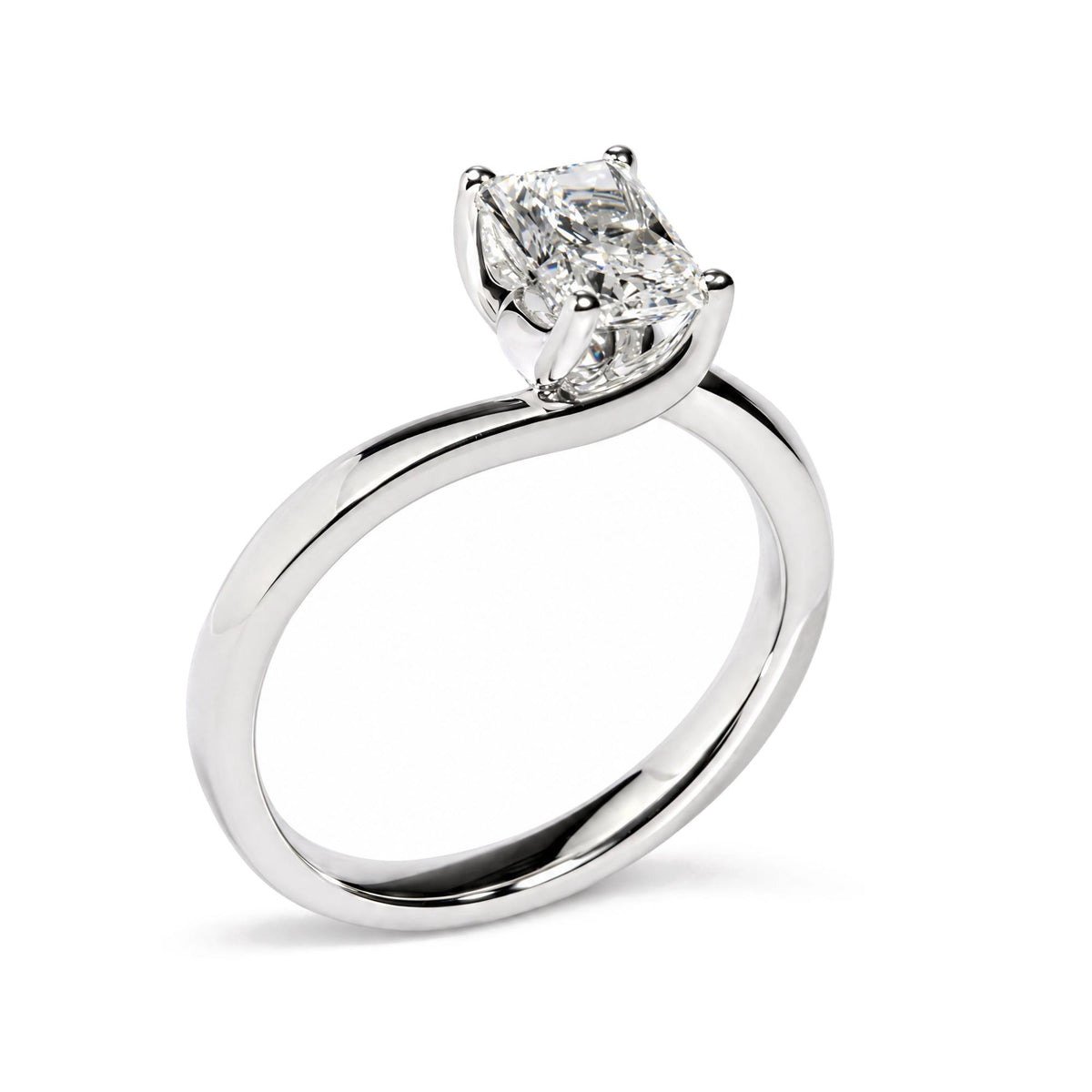 Close-up side angle of a white metal ring with a single radiant-shaped white gemstone in a prong setting.