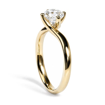 Close-up front angle of a yellow ring with a twisted band design, featuring a single round white gemstone in a prong setting.