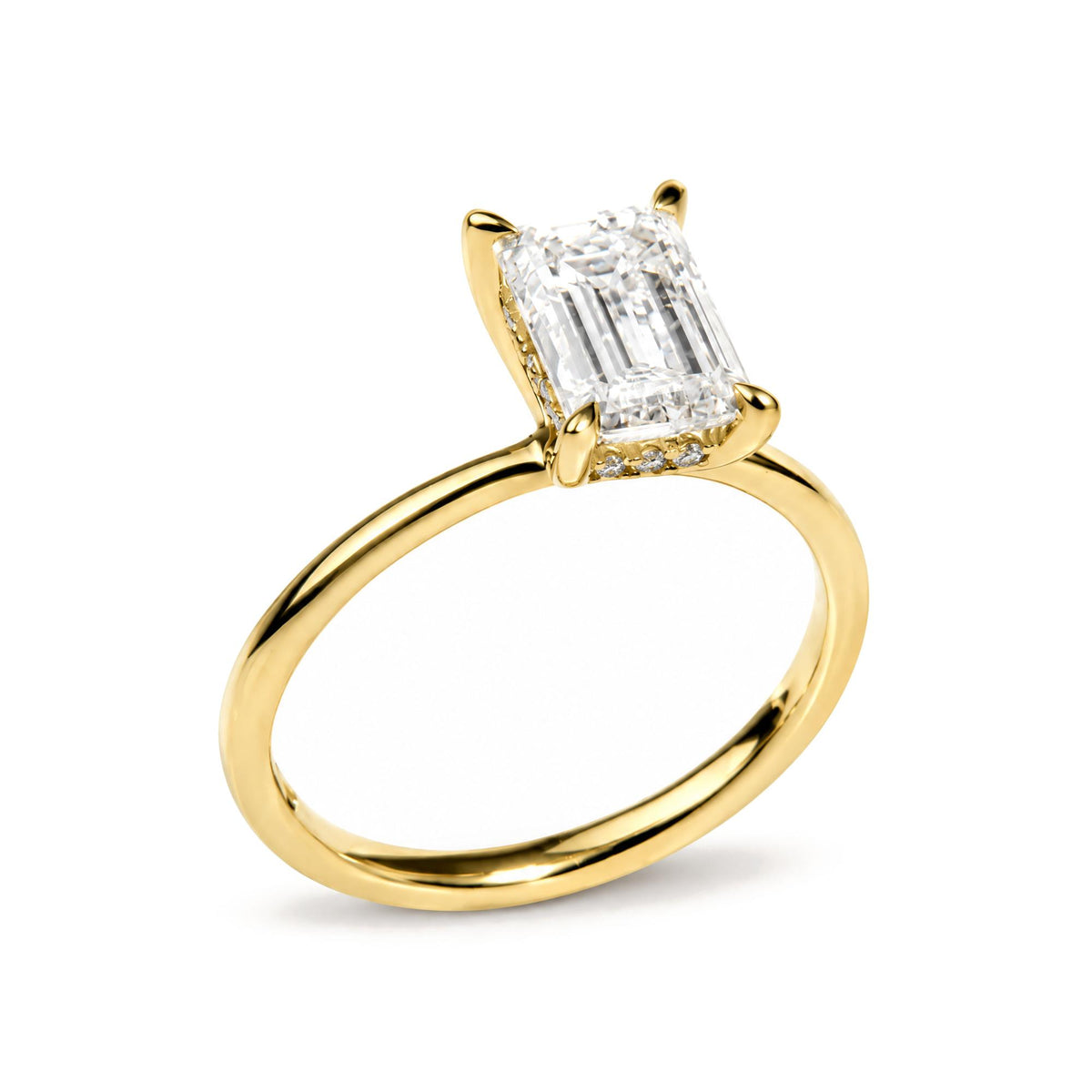 Close-up of a yellow ring with a large emerald-shaped white gemstone in prong setting, surrounded by smaller round white gemstones on the band, shown at an angled view.