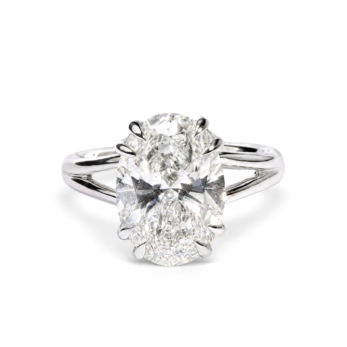 Close-up front view of a white metal ring featuring a single oval-shaped white gemstone in a double claw prong setting.