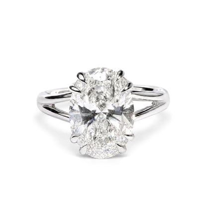 Close-up front view of a white metal ring featuring a single oval-shaped white gemstone in a double claw prong setting.