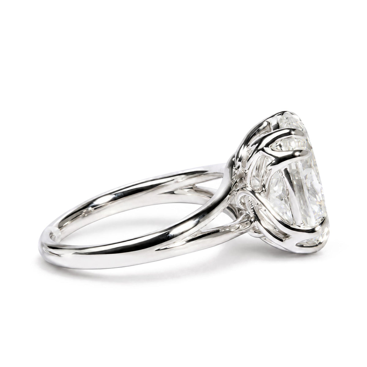 Close-up side angle of a white metal ring featuring an oval-shaped white gemstone in a double claw prong setting.