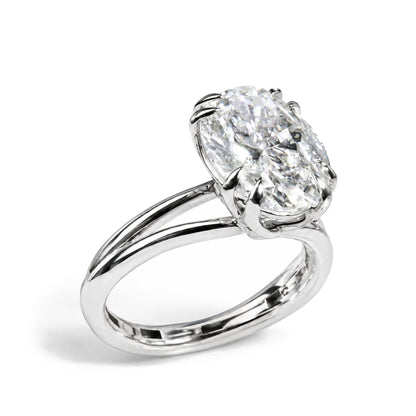Close-up angle of a white metal ring with a large oval-shaped white gemstone held by a double claw prong setting.