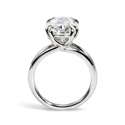 Close-up front view of a white metal ring featuring a single oval-shaped white gemstone in a double claw prong setting.