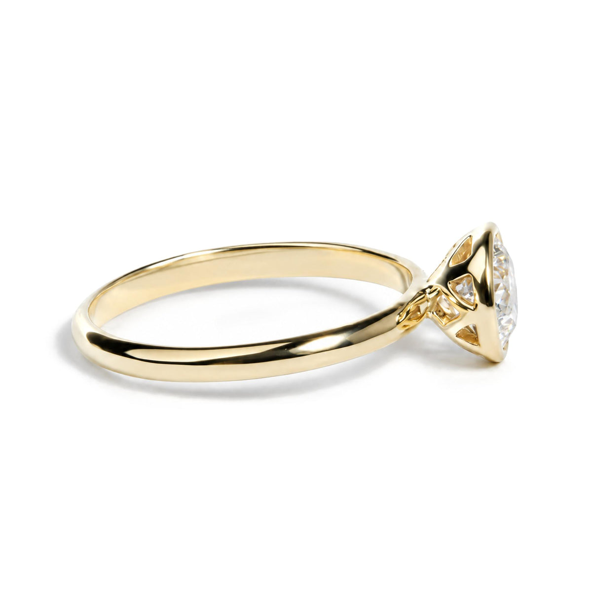 Close-up side view of a yellow metal ring with a white emerald-shaped gemstone in a bezel setting.