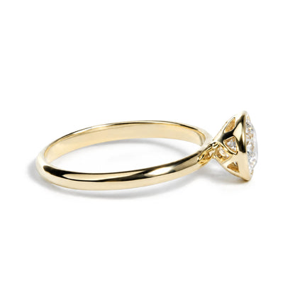 Close-up side view of a yellow metal ring with a white emerald-shaped gemstone in a bezel setting.