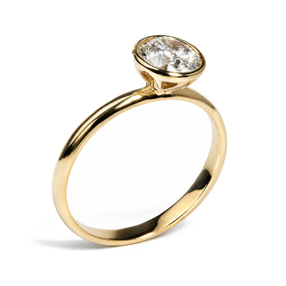 Close-up front angle of a yellow metal ring featuring a single white emerald-shaped gemstone in a bezel setting.