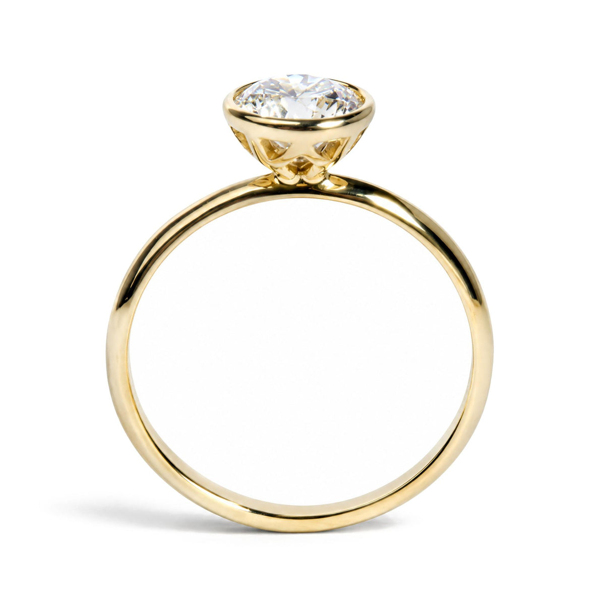 Close-up front angle of a yellow metal ring with a white gemstone in an emerald shape bezel setting.