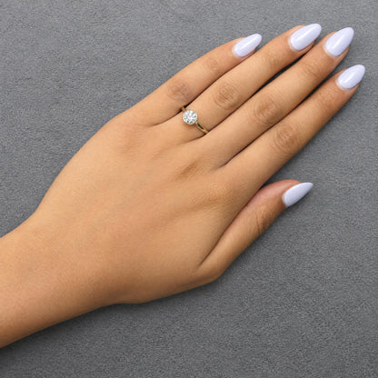 Yellow metal ring with a single white gemstone in a bezel setting, shown worn on a model's hand from a top angle.