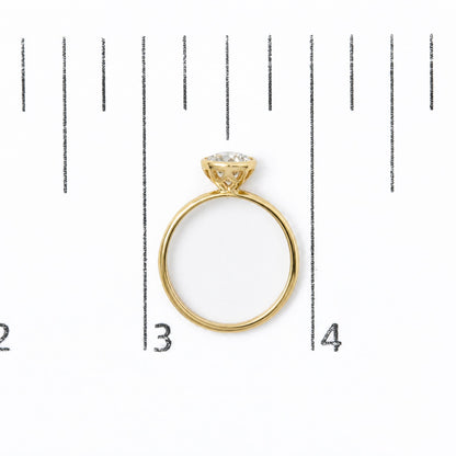 Yellow ring with a white emerald-shaped gemstone in a bezel setting, shown from a top-down angle on a size scale.