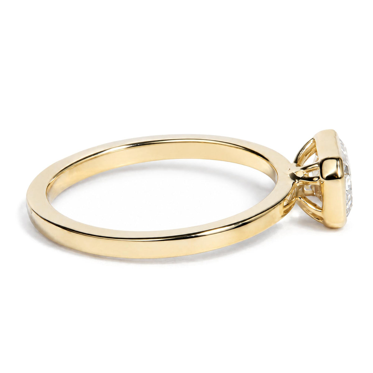 Close-up side-angle view of a yellow metal ring featuring a white emerald-shaped gemstone in a bezel setting.