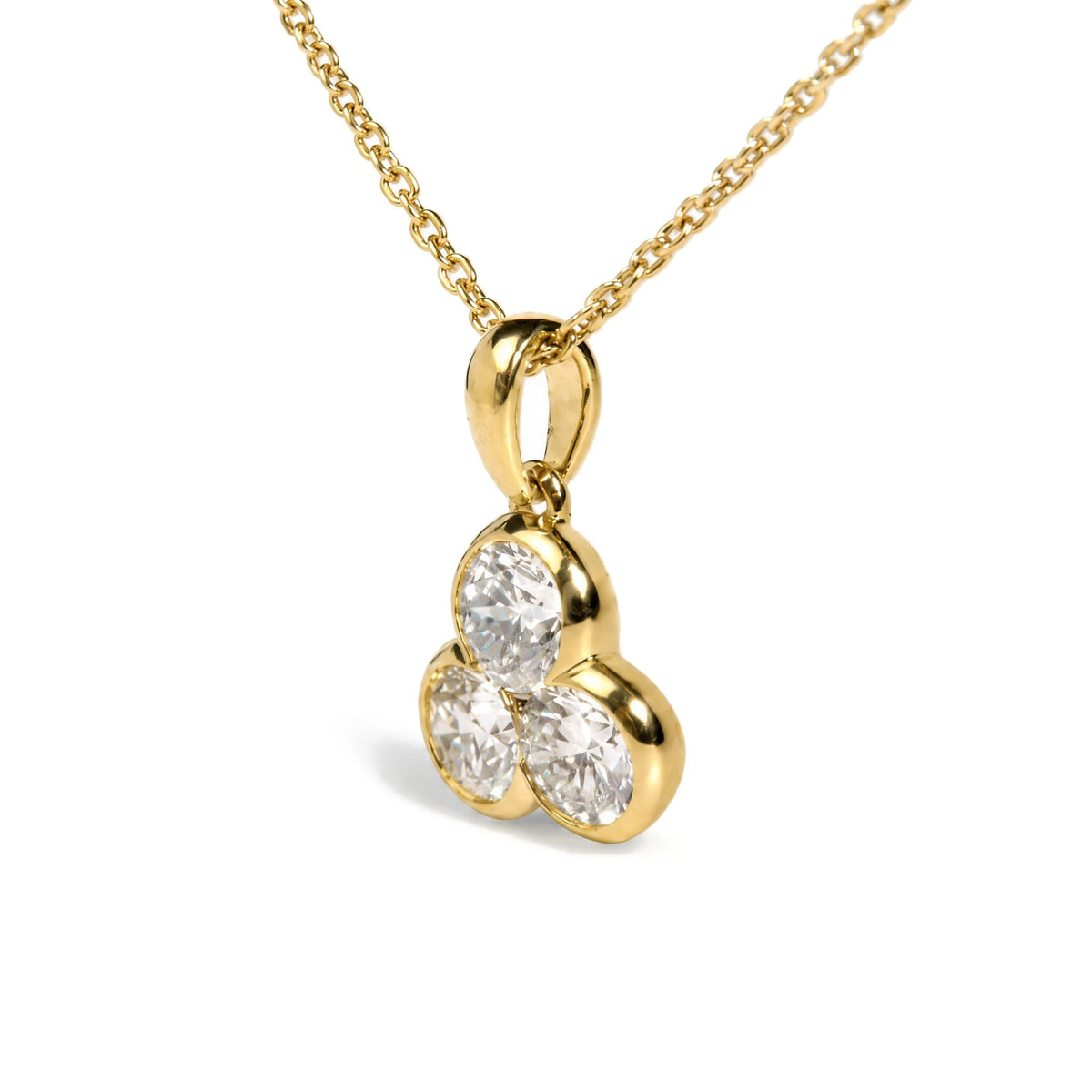 Close-up angled view of a yellow metal necklace with a pendant featuring three round white gemstones in bezel settings.