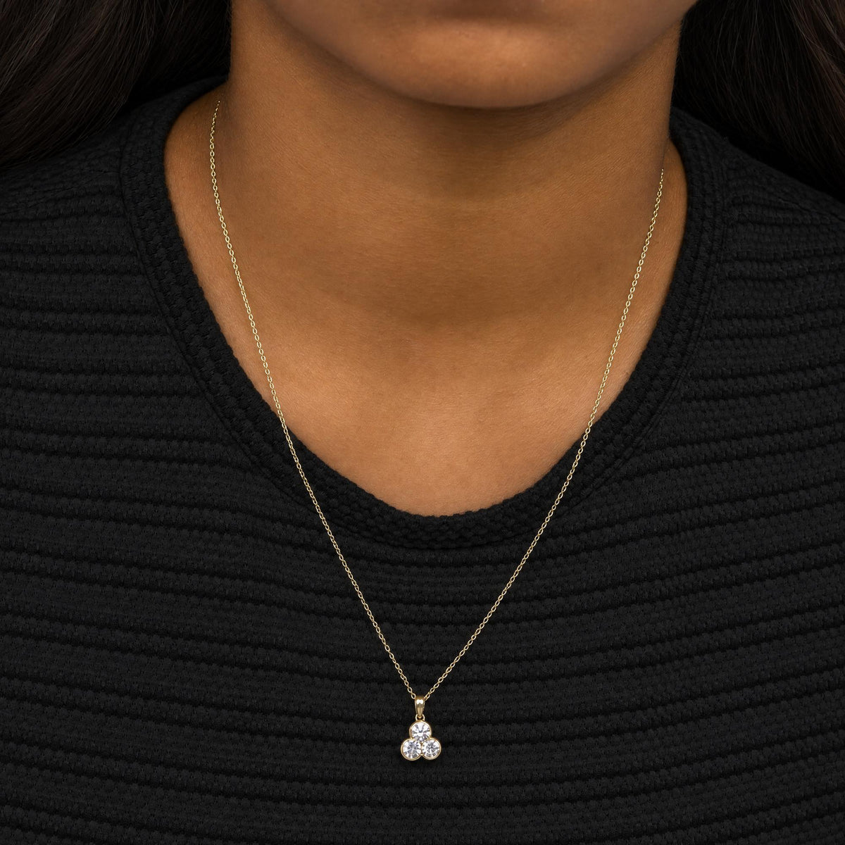 Yellow necklace with a trio of round white gemstones in bezel settings pendant, shown worn on a model, front angle.