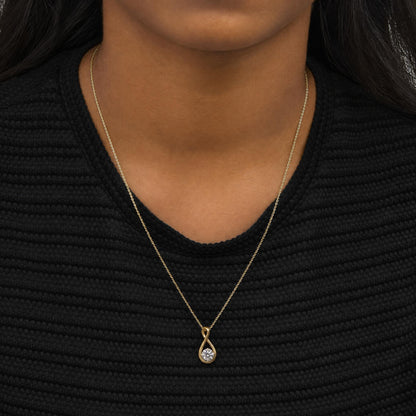 Close-up front view of a model wearing a yellow metal necklace with an infinity-shaped pendant featuring a round white gemstone in a bezel setting.