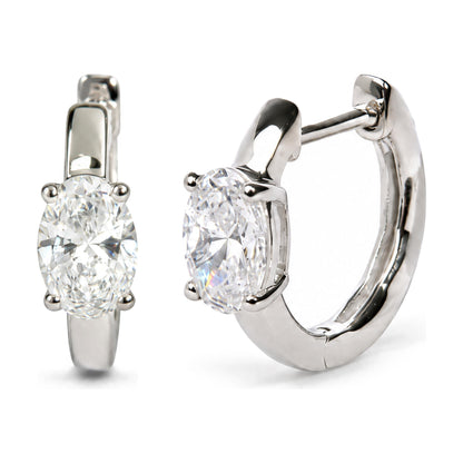 Close-up image of a pair of white metal hoop earrings with oval-shaped white gemstones set in a four-prong setting, shown from a front and side angle on a white background.