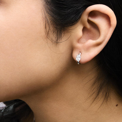 Close-up side view of a model wearing white metal earrings featuring oval-shaped white gemstones in 4-prong settings.