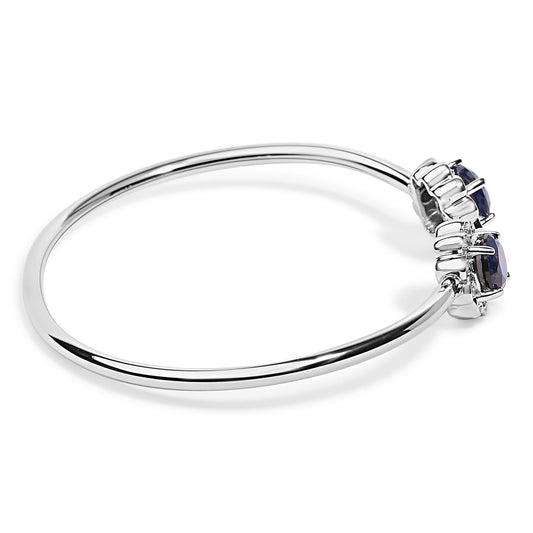 White metal bracelet with two large blue gemstones flanked by multiple small white gemstones, shown on a white background from a side angle.