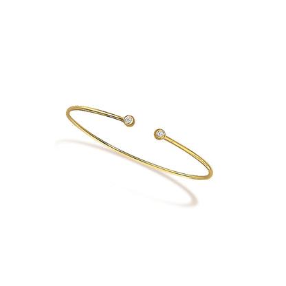 Open yellow metal bracelet with round white gemstones in bezel settings at each end, shown at a slight angle.