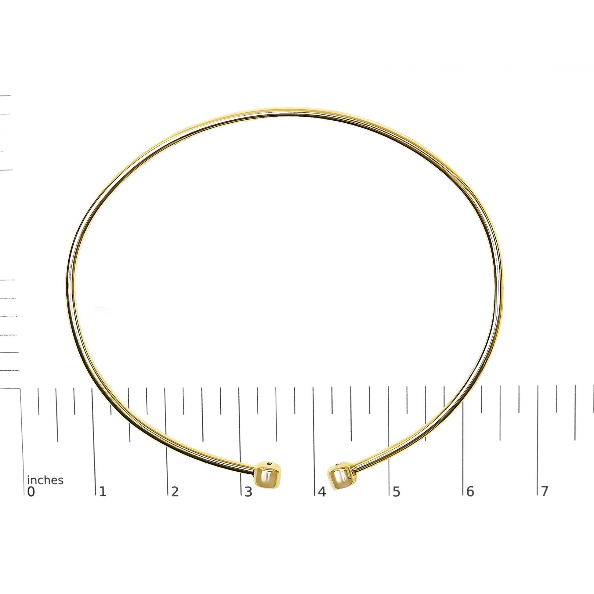 Bracelet in yellow and white metal with round white gemstones in bezel settings at open ends, shown on a scale, front angle.