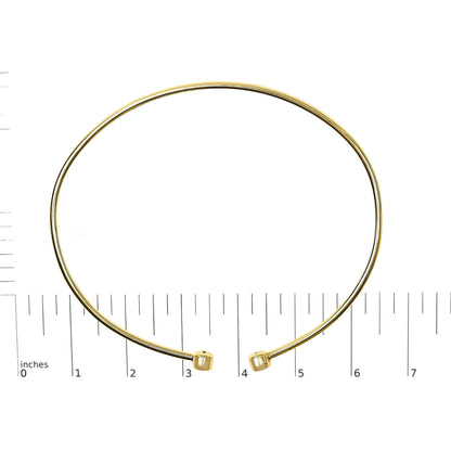 Bracelet in yellow and white metal with round white gemstones in bezel settings at open ends, shown on a scale, front angle.
