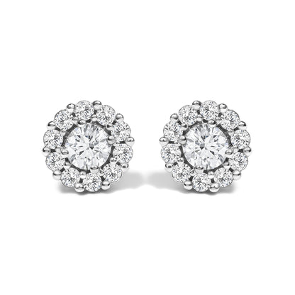 Pair of white metal round stud earrings with a central round white gemstone in four-prong setting, surrounded by smaller round white gemstones in shared prong setting, shown from the front on a white background.