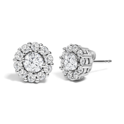 Front and side angled view of white metal stud earrings featuring a central round gemstone in 4-prong setting, surrounded by a cluster of smaller round gemstones in shared prong setting.