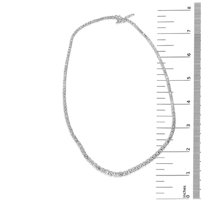 Top-down view of a white metal necklace with two sizes of round white gemstones in four-prong settings, placed on a ruler for size reference.