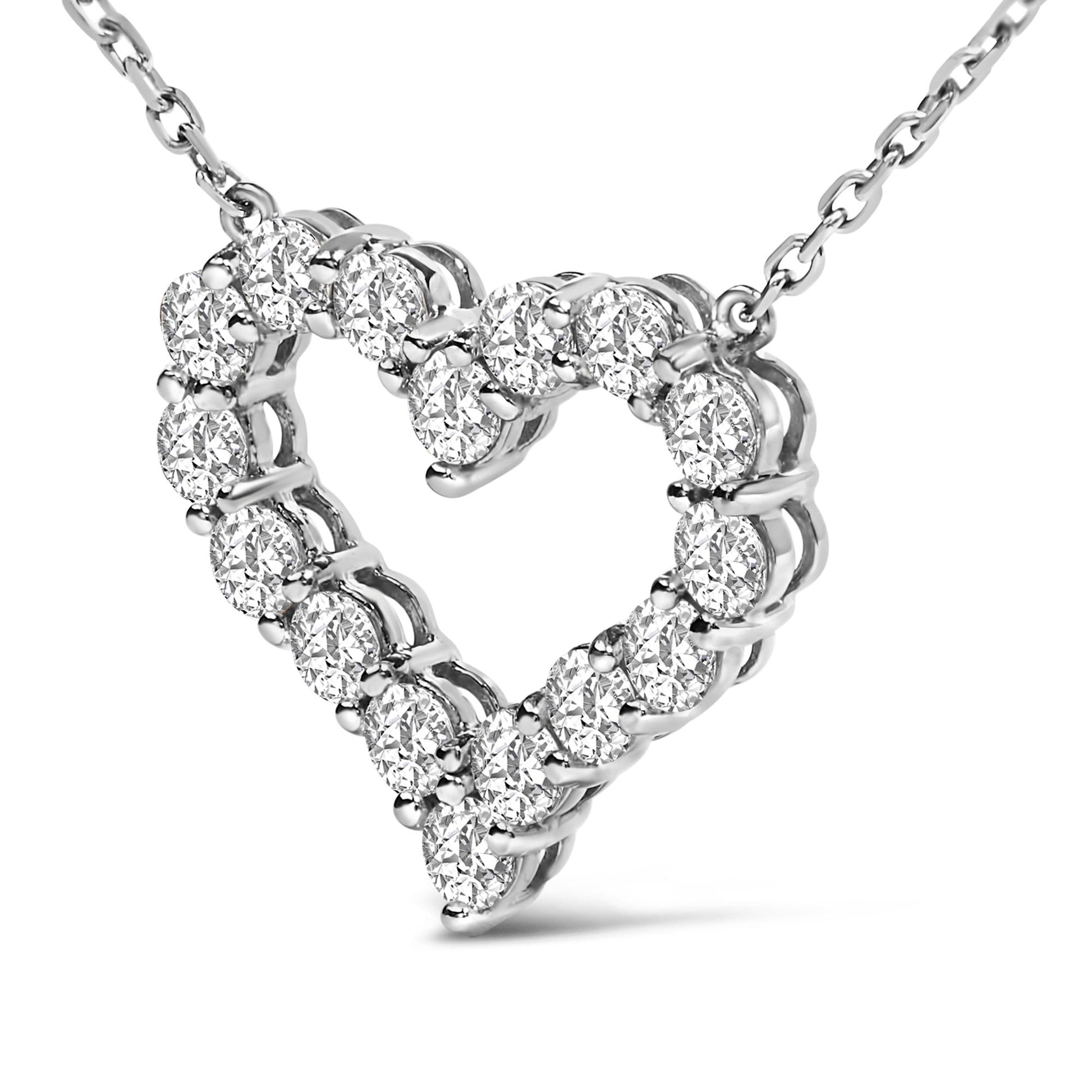 Close-up front angle of a white heart-shaped necklace pendant with round white gemstones in a shared prong setting on a white chain.