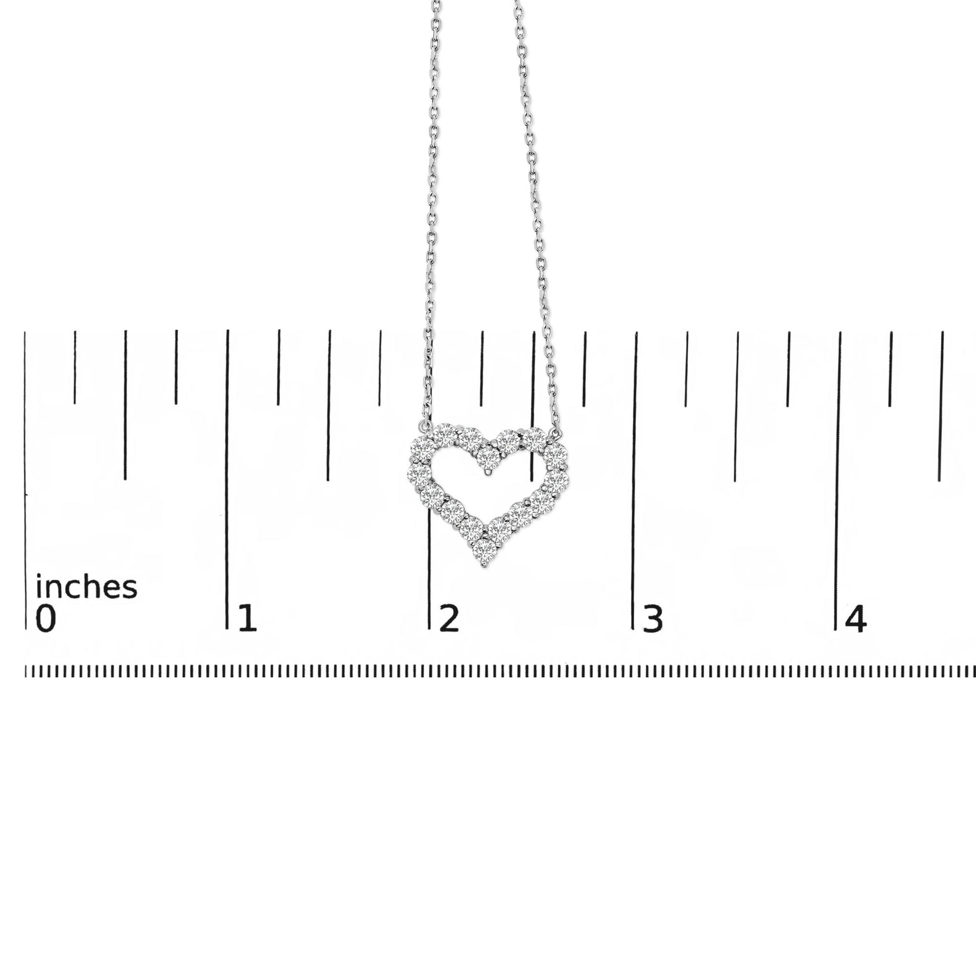 White metal necklace with heart-shaped pendant made of round white gemstones in shared prong setting, shown hanging centered on a ruler for scale, front view.