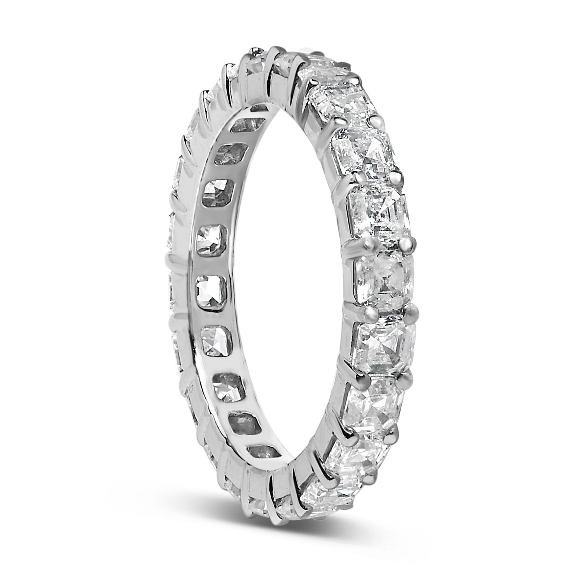 White metal ring with asscher-shaped white gemstones in shared prong setting encircling the band, shown at a slight angle.