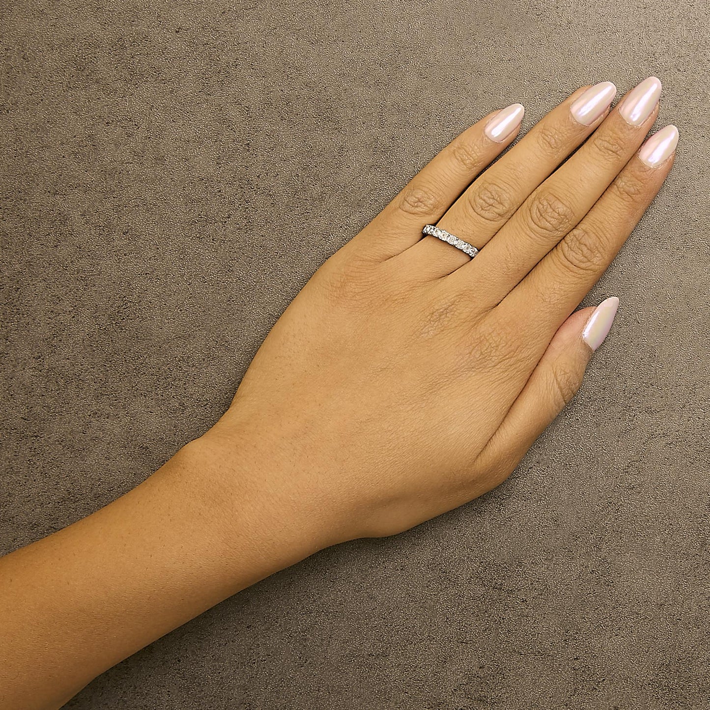 White metal ring with multiple white asscher-shaped gemstones in shared prong setting, shown worn on a model's hand from a top-down angle.