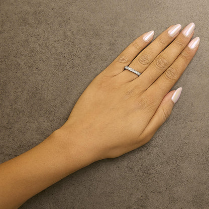 White metal ring with multiple white asscher-shaped gemstones in shared prong setting, shown worn on a model's hand from a top-down angle.