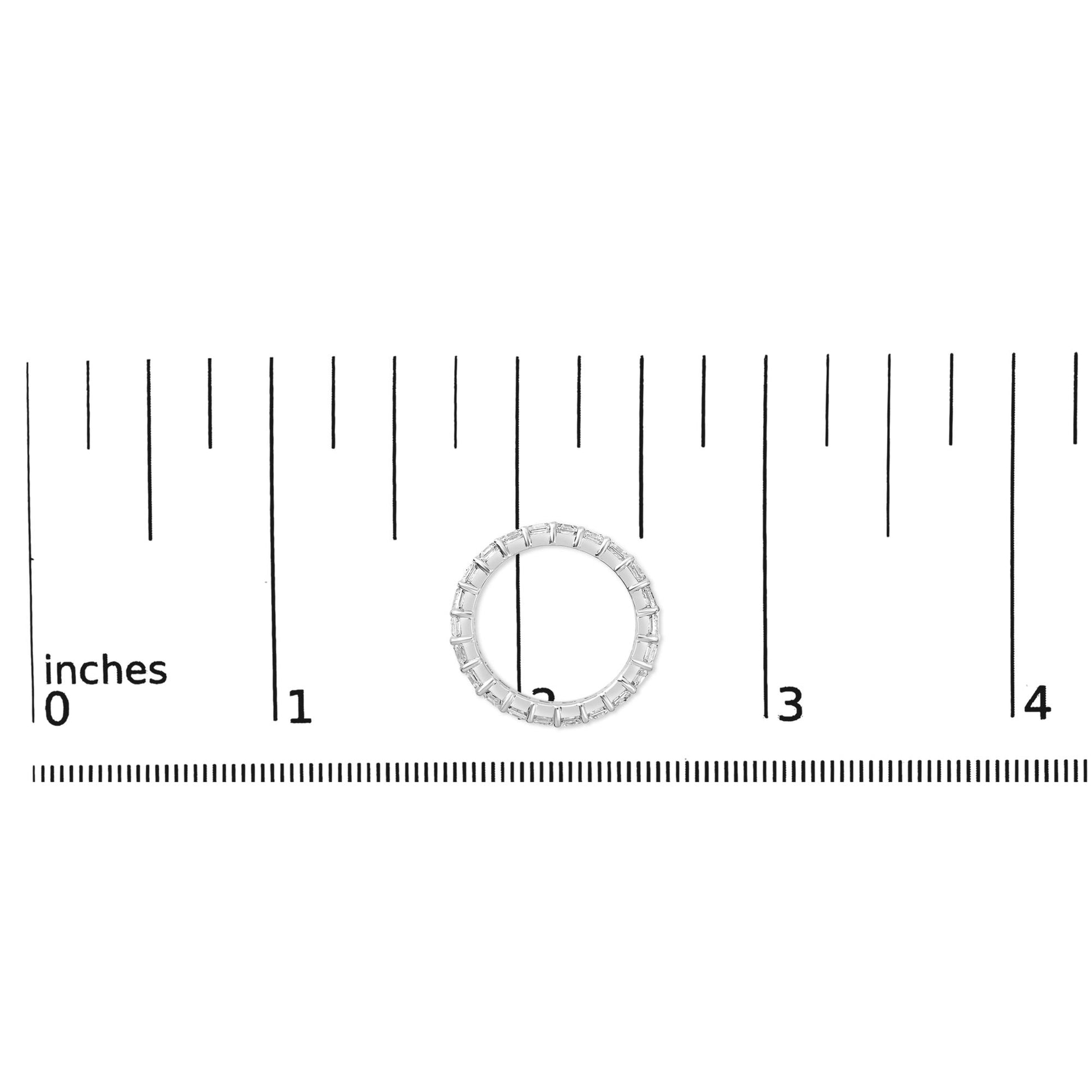 White metal ring with asscher-shaped white gemstones in a shared prong setting, shown flat on a measuring scale, top-down view.