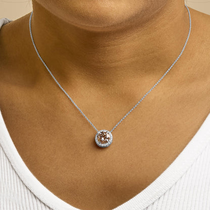 White metal necklace with a round pink gemstone surrounded by smaller white gemstones, worn on a model, front-facing close-up shot.
