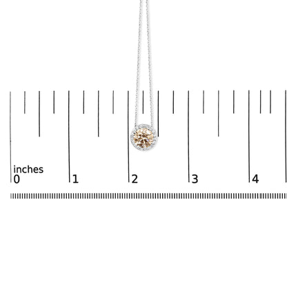 Close-up front view of a white necklace pendant with a central round pink gemstone surrounded by smaller white round gemstones, displayed on a ruler for size reference.