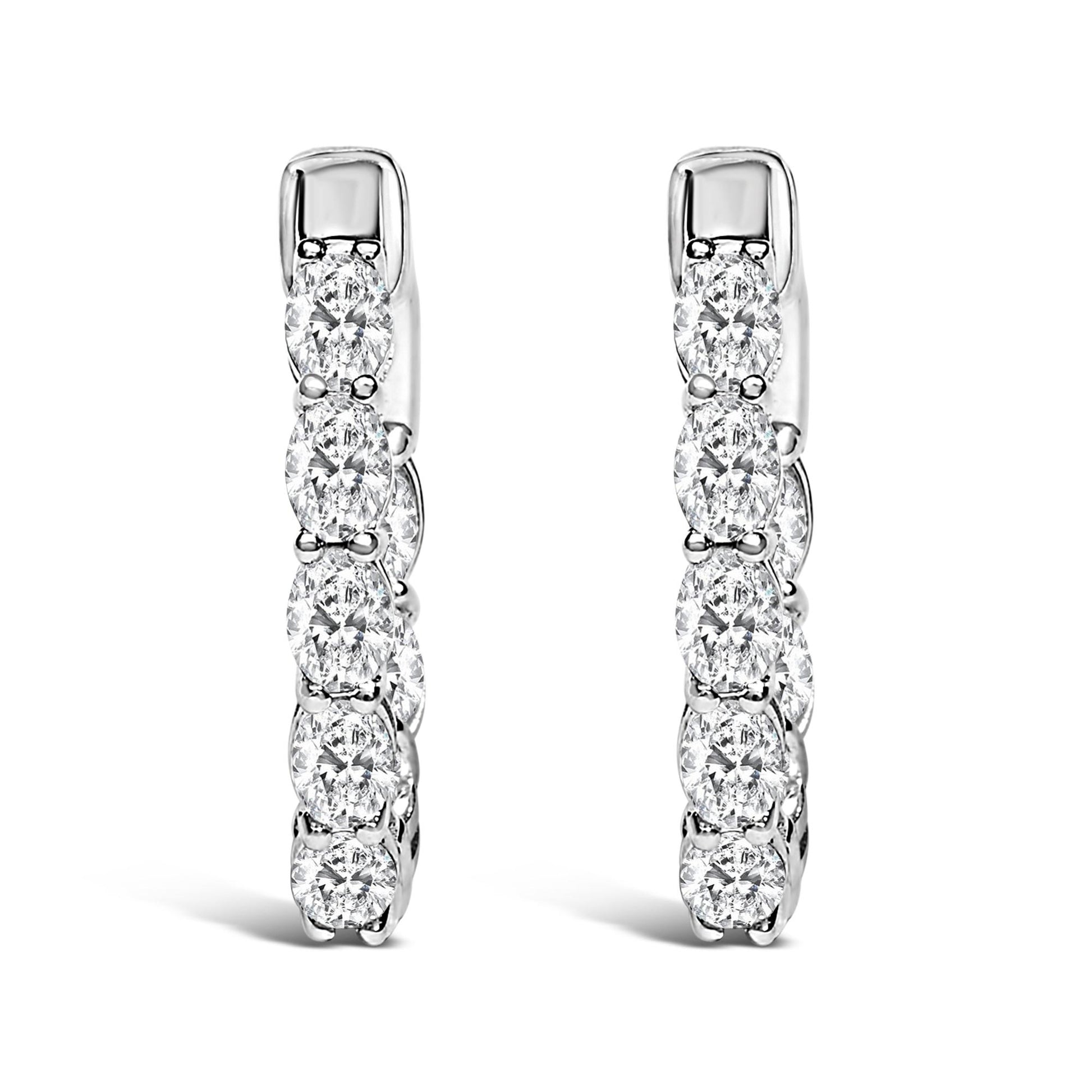 Pair of vertical white metal hoop earrings with oval-shaped white gemstones in a shared prong setting, shown in a front-facing close-up angle on a white background.