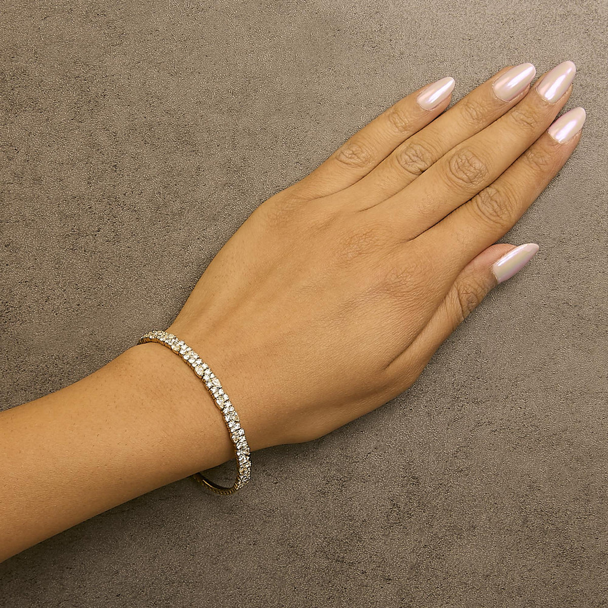 Yellow bracelet with pear and round white gemstones in prong settings, shown worn on a model's wrist, angled top-down.
