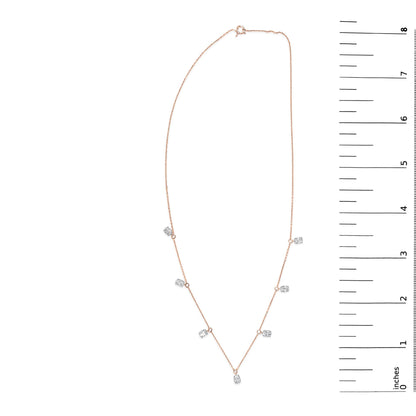 Rose-colored necklace with seven oval-shaped white gemstones in 4-prong settings, laid flat and shown next to a vertical scale.