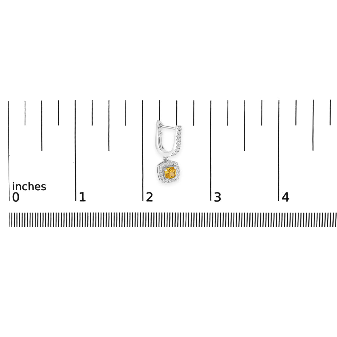 Single white metal earring with a yellow cushion-shaped gemstone surrounded by small round white gemstones, shown on a scale from a top-down angle.