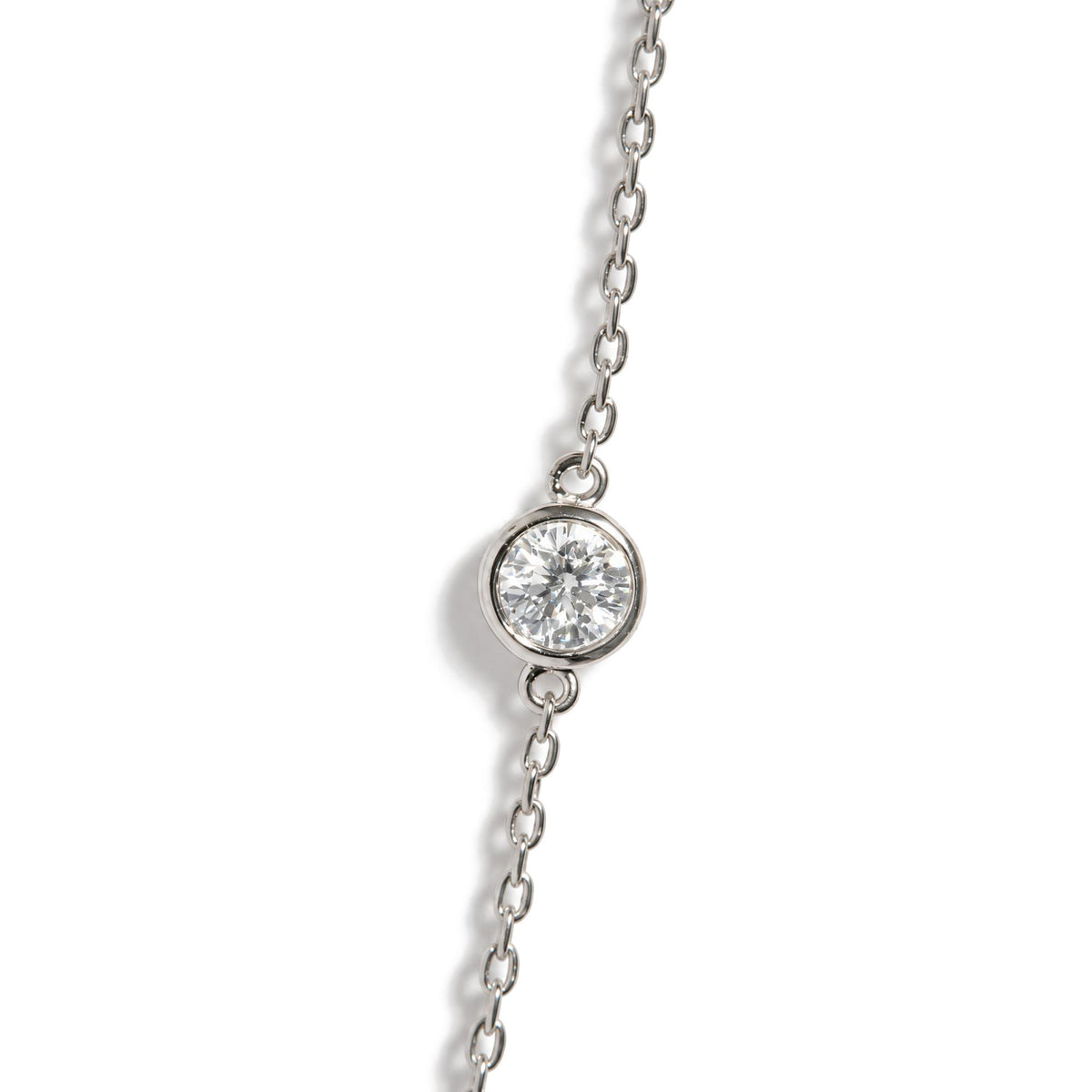 Close-up top angle view of a white metal necklace chain featuring a round white gemstone in a bezel setting.