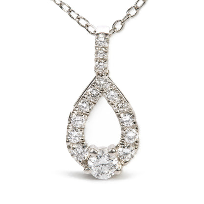 Close-up front angled shot of a white metal necklace pendant featuring a teardrop shape outlined with round white gemstones in prong settings and a larger round white gemstone at the bottom center, with a chain of oval links.