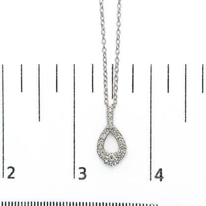 Close-up front view of a white necklace pendant with round white gemstones in a prong setting, shown on a scale.