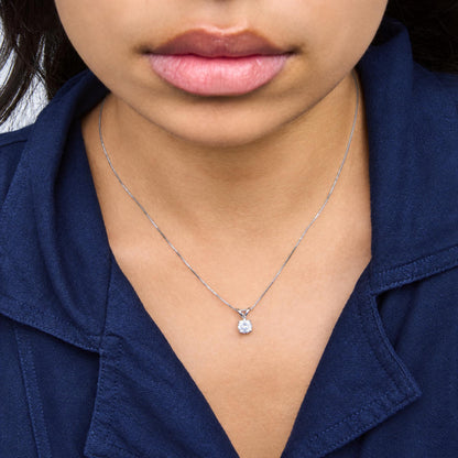 Close-up frontal view of a model wearing a white metal necklace with a single round white gemstone in a prong setting pendant.