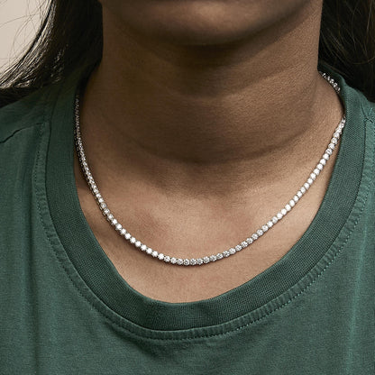 Close-up front view of a yellow metal necklace with round white gemstones in a 4-prong setting, shown worn on a model.