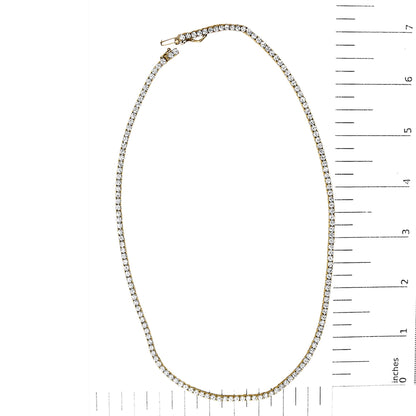 Yellow metal necklace with round white gemstones in a 4-prong setting, shown flat on a scale with rulers.
