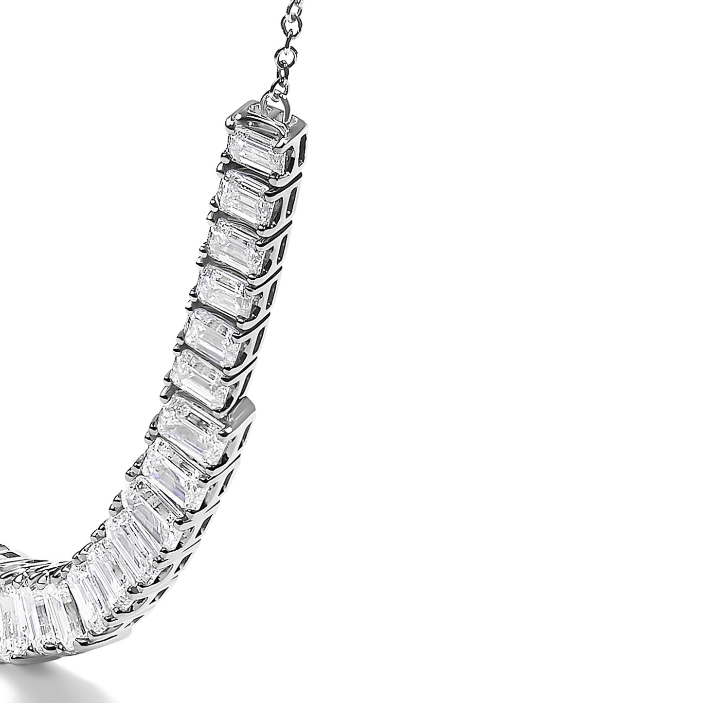 Close-up angled view of a white necklace featuring a curved row of emerald-shaped white gemstones in four-prong settings.